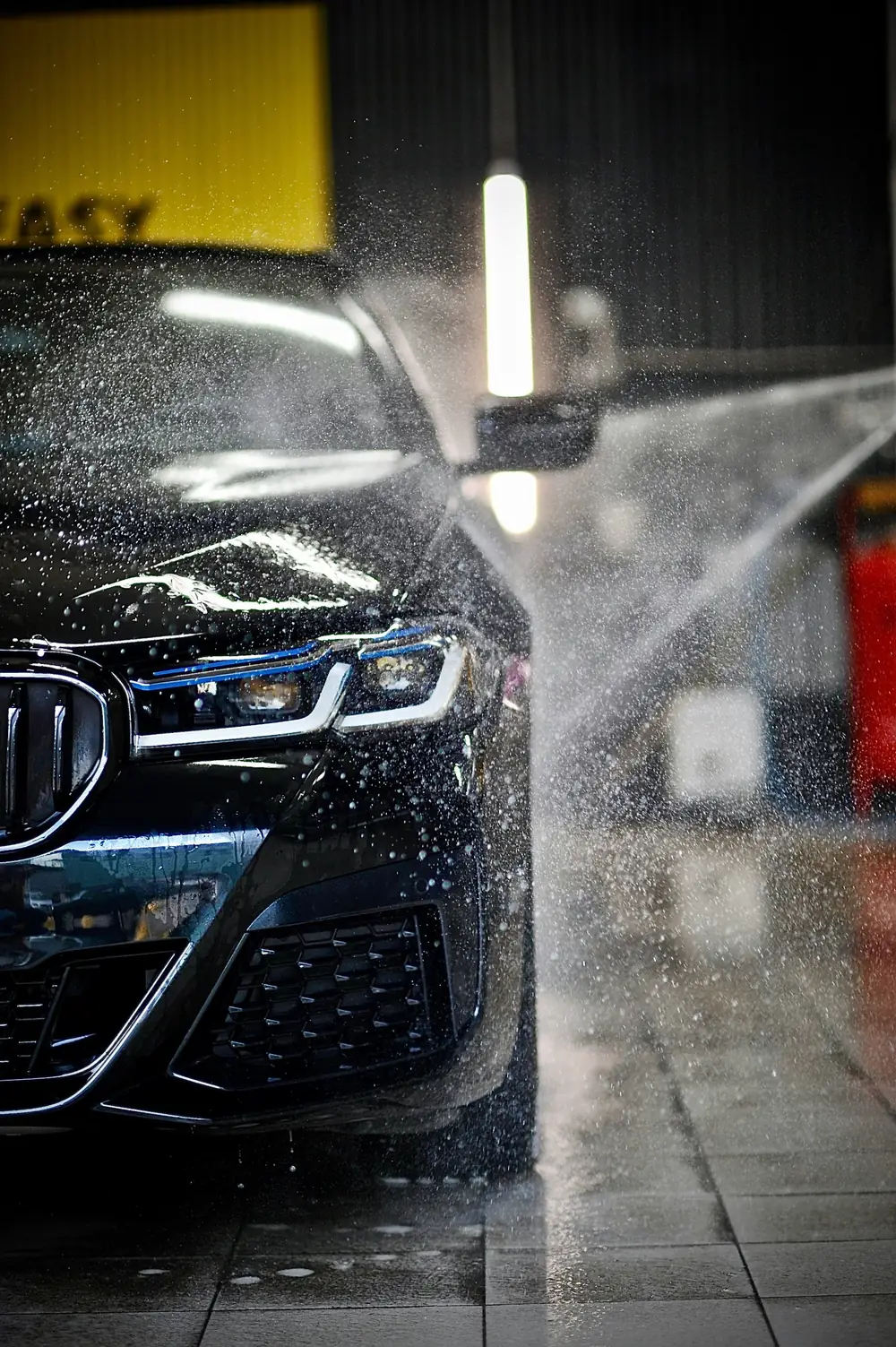 Zwarte wagen wordt afgespoten in een carwash